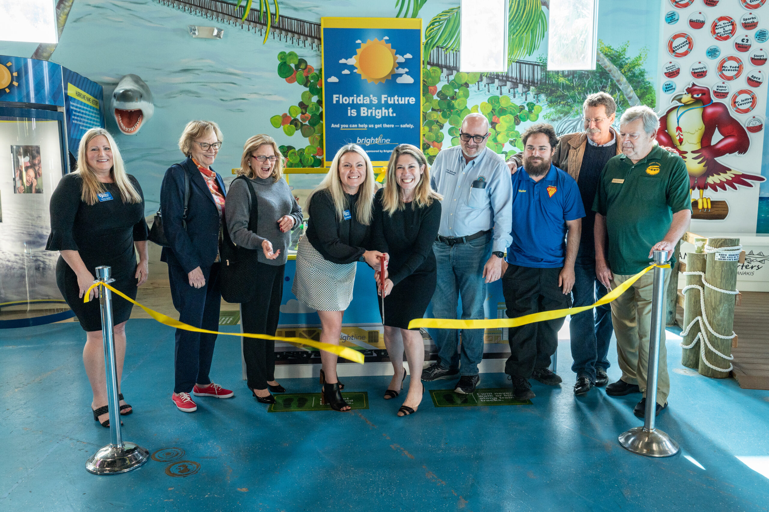 Brightline and The Children's Museum team cutting a yellow ribbon for the new Brightline Trains safety exhibit